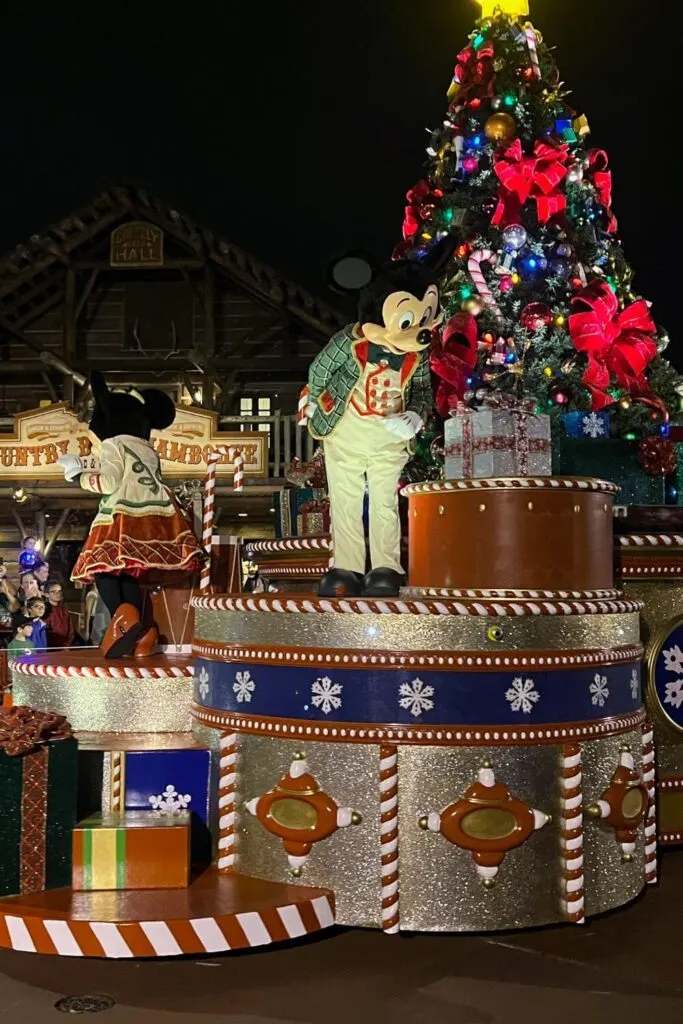 Photo of Mickey and Minnie Mouse dressed in fancy holiday outfits while on a Christmas themed parade float.