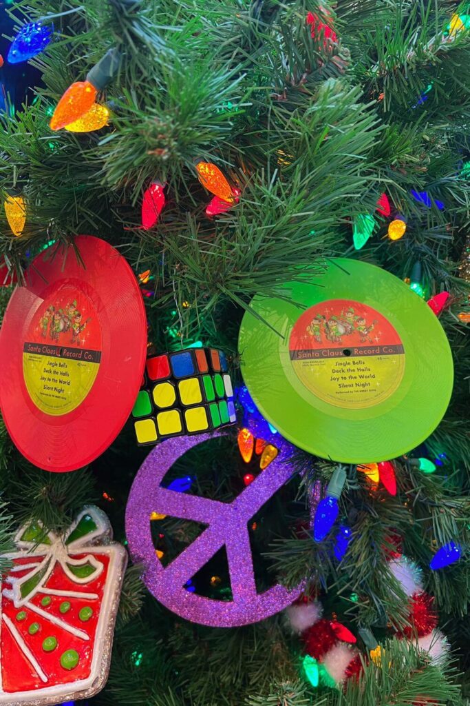 Closeup of retro Christmas ornaments, such as a peace sign, Rubik's Cube, and records, on a Christmas tree in Disney's Pop Century resort lobby.