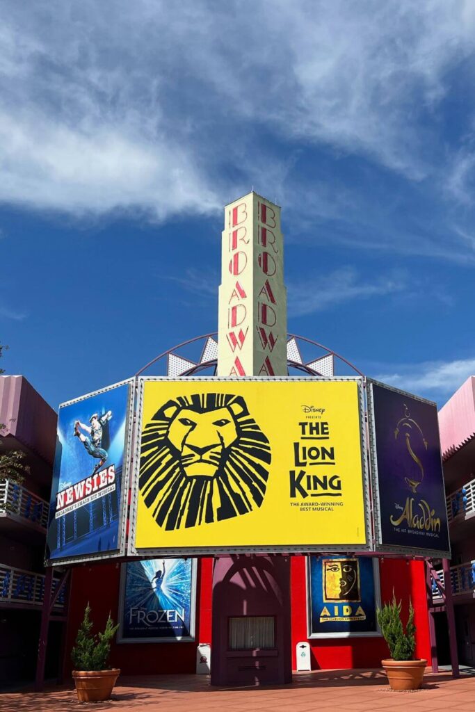 Photo of faux broadway advertisements on a hotel building, featuring Newsies, The Lion King, Aladdin, Frozen, and AIDA.