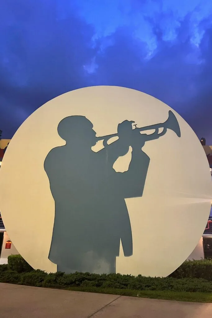 Photo of a large art piece with a silhouette of a person playing a trumpet with dark skies in the background.