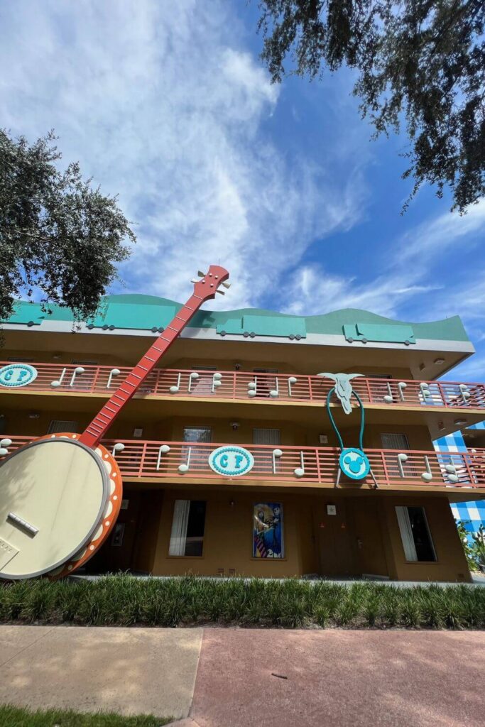 Photo of a group of rooms at All Star Music Resort in the Country Fair section with a giant banjo and southwestern style bolo tie on the railings.