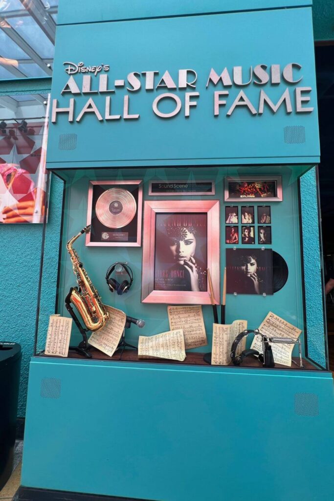 Photo of a museum-like display featuring photos, instruments, and records of Janet Jackson. Text on the display reads: Disney's All-Star Music Hall of Fame.