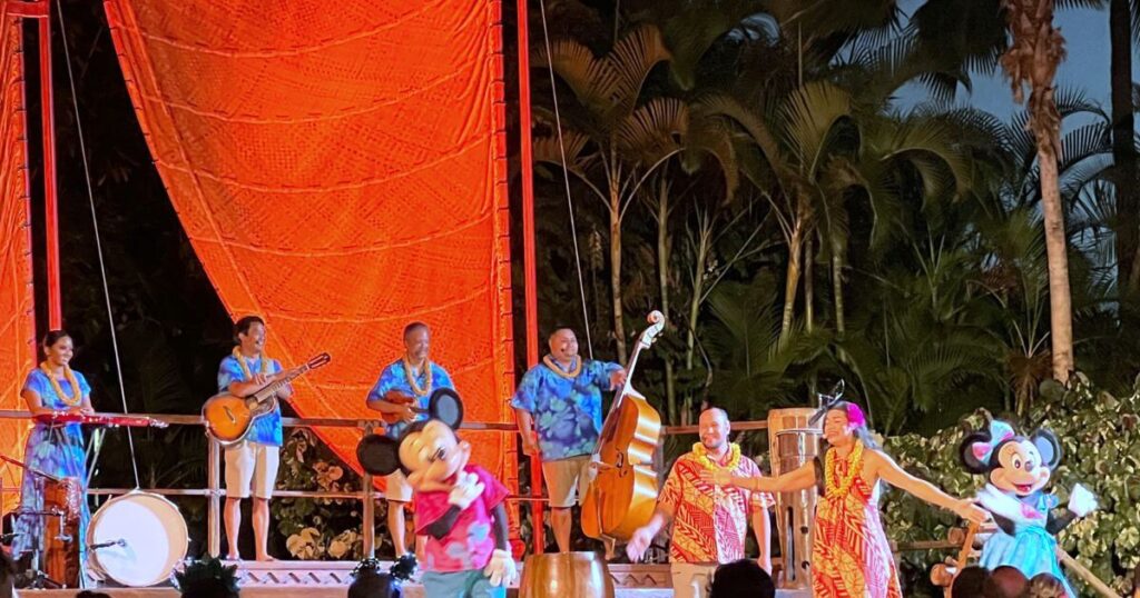 Photo of Mickey and Minnie Mouse dancing on stage with the performers at the Ka Wa'a luau at Aulani Disney Resort.