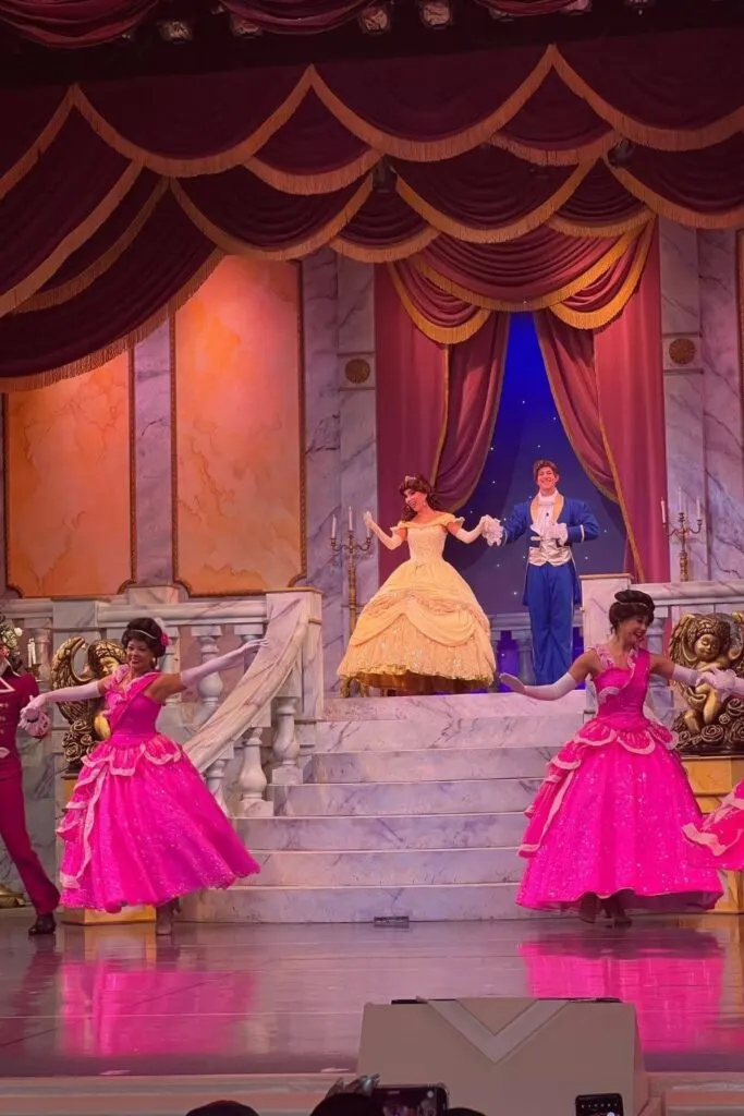 Photo of Belle and the Prince in the Hollywood Studios stage show, walking down steps with dancers at the end of the steps.