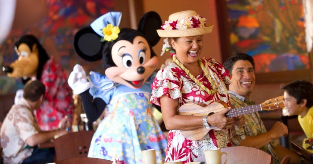 Photo of a woman playing an ukulele while Minnie Mouse and Goofy greet guests at the Makahiki character breakfast.
