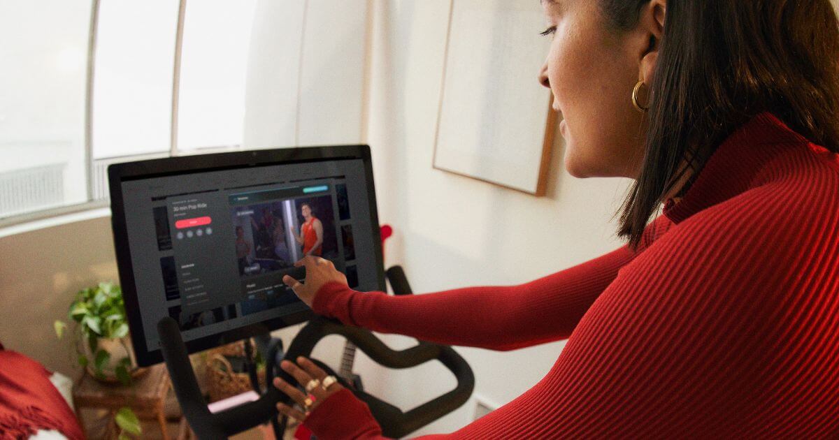 Photo of a woman browsing through the Peloton bike interface, open to a class.