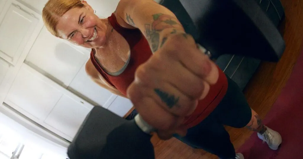 Photo of a woman working out at home with hand weights.