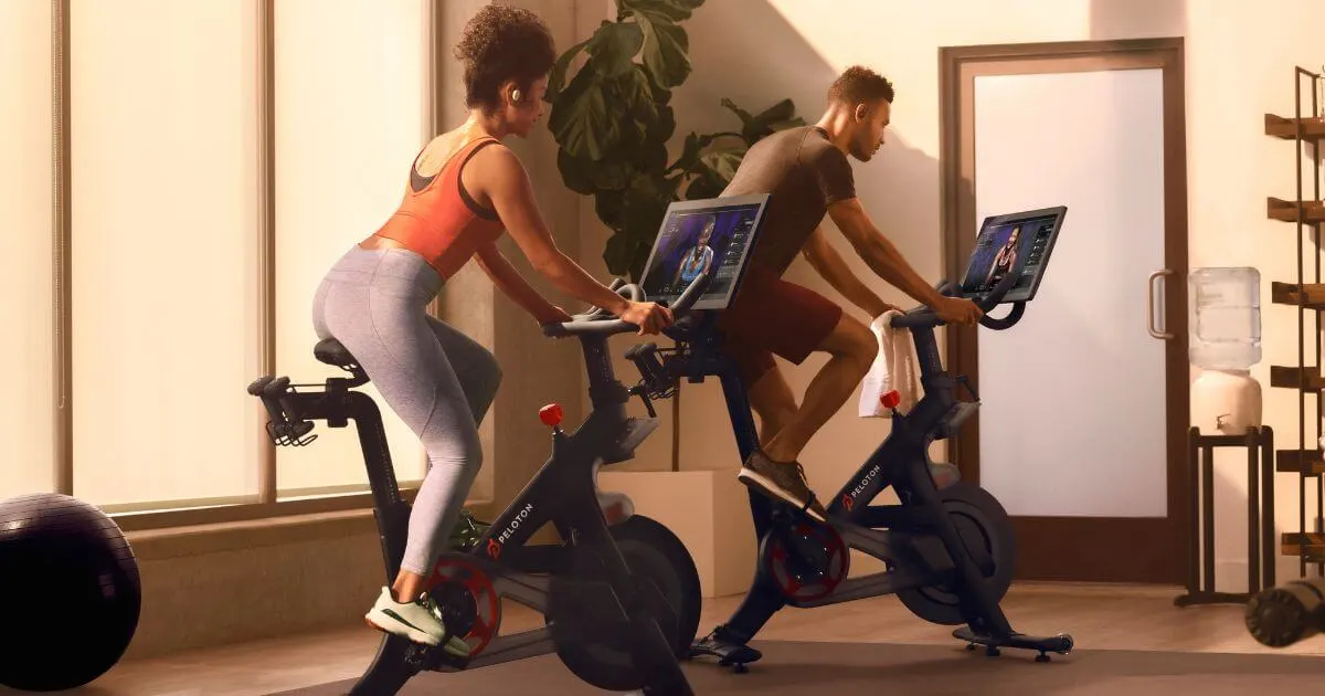 Photo of a man and a woman working out on Peloton bikes in a hotel gym.