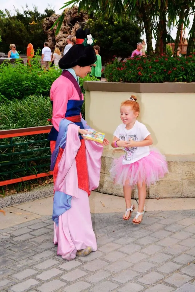 Photo of a young girl jumping up with joy as she meets Mulan in Epcot's China pavilion.