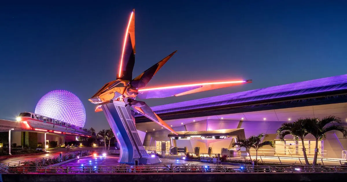 Photo of the Xandar pavilion in Epcot at night with the monorail going by and Spaceship Earth in the background.