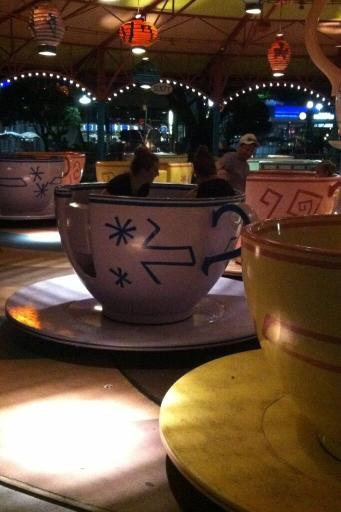 Photo of the Mad Tea Party ride at night, with tea cup seats twirling in action.