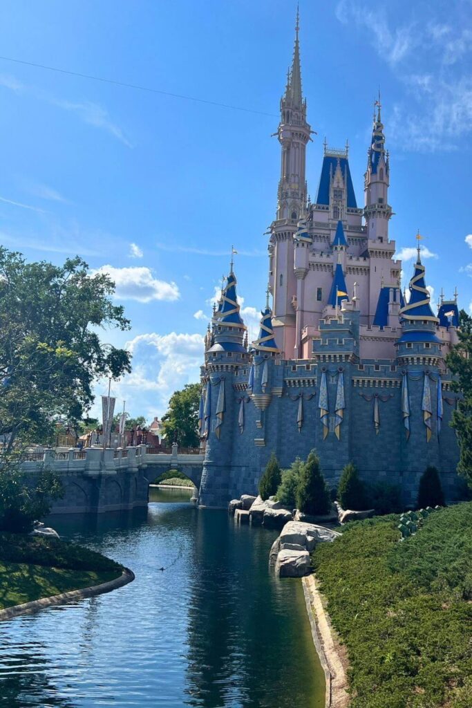 Photo of Cinderella Castle from the side, reflecting in a moat in the foreground.