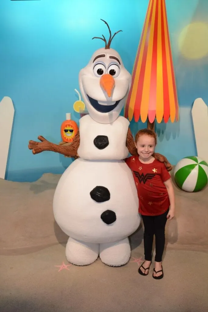 Photo of a young girl posing for a photo with Olaf at Hollywood Studios.