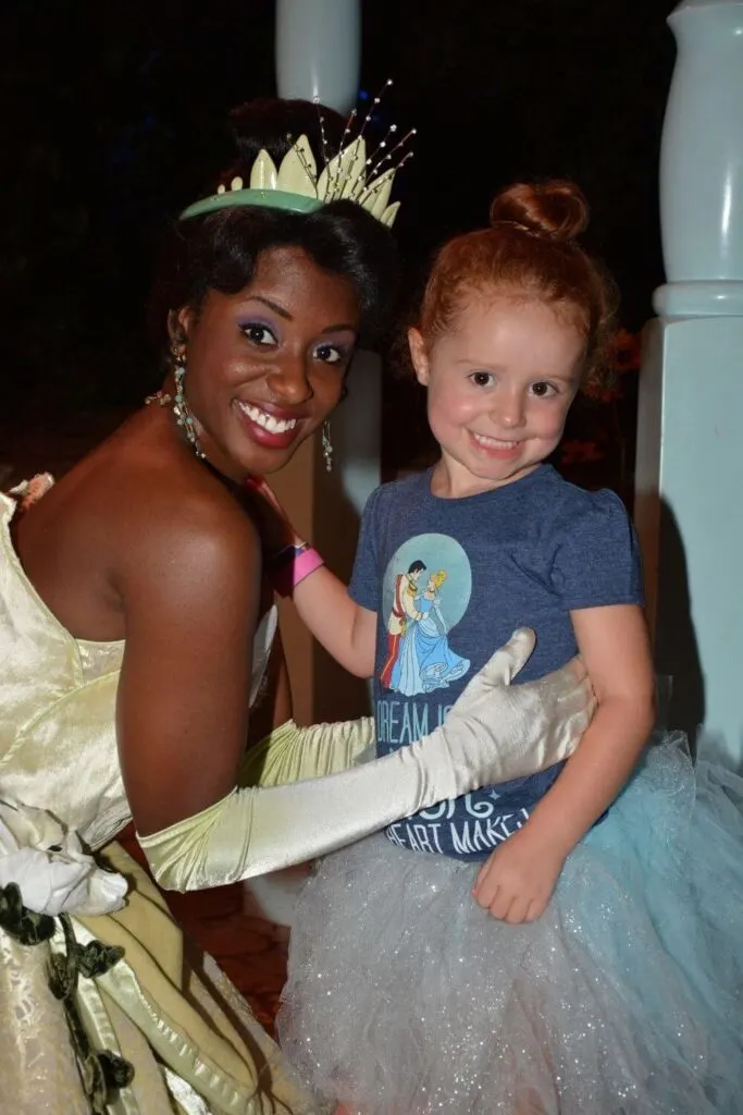 Photo of a young girl dressed as Cinderella posing with Princess Tiana.