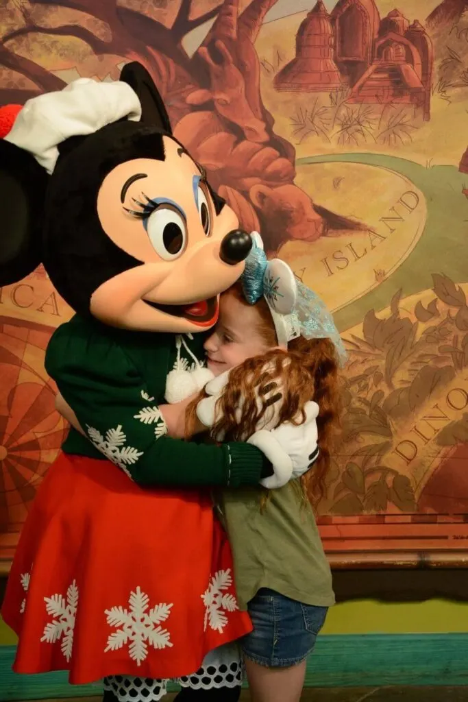 Photo of a young girl hugging Minnie Mouse in a Christmas outfit at the Animal Kingdom meet-and-greet.