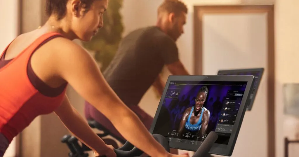 Closeup photo of a woman and man working out on Peloton bikes at a hotel fitness center.