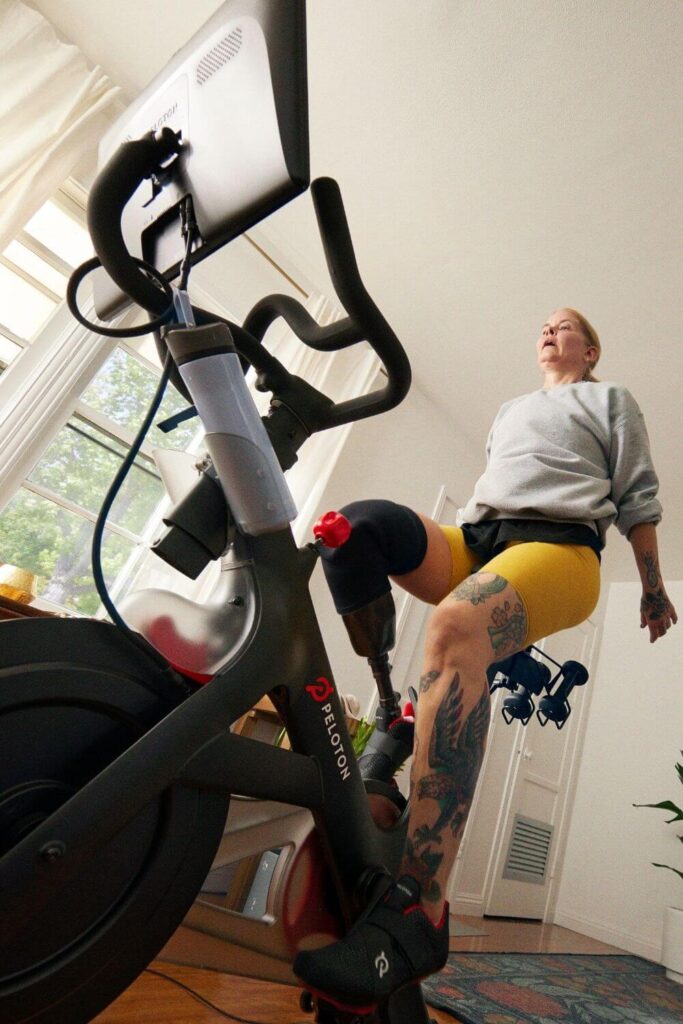 Photo of a woman with a prosthetic leg exercising on a Peloton bike.