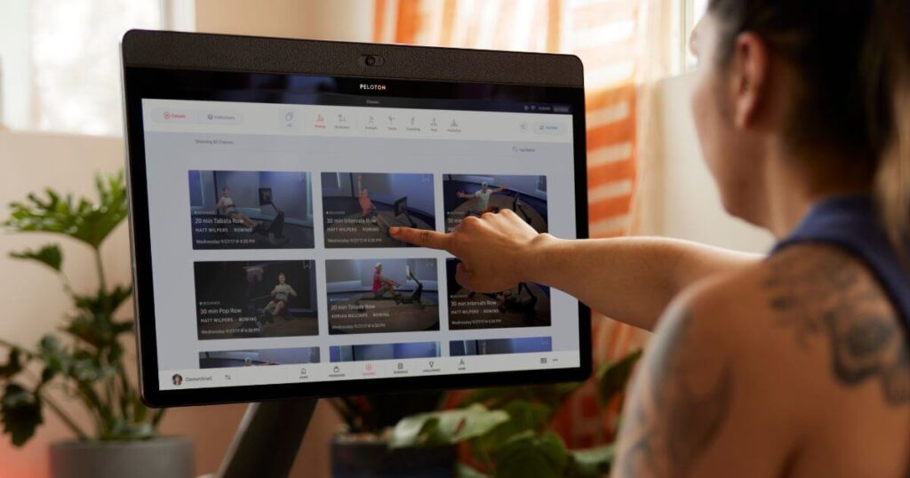 Photo of a woman browsing Peloton rowing classes on the Peloton rower.