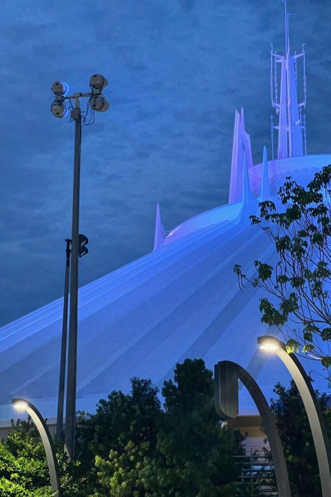 Photo of the roof of Space Mountain at Magic Kingdom lit up in blue at night.