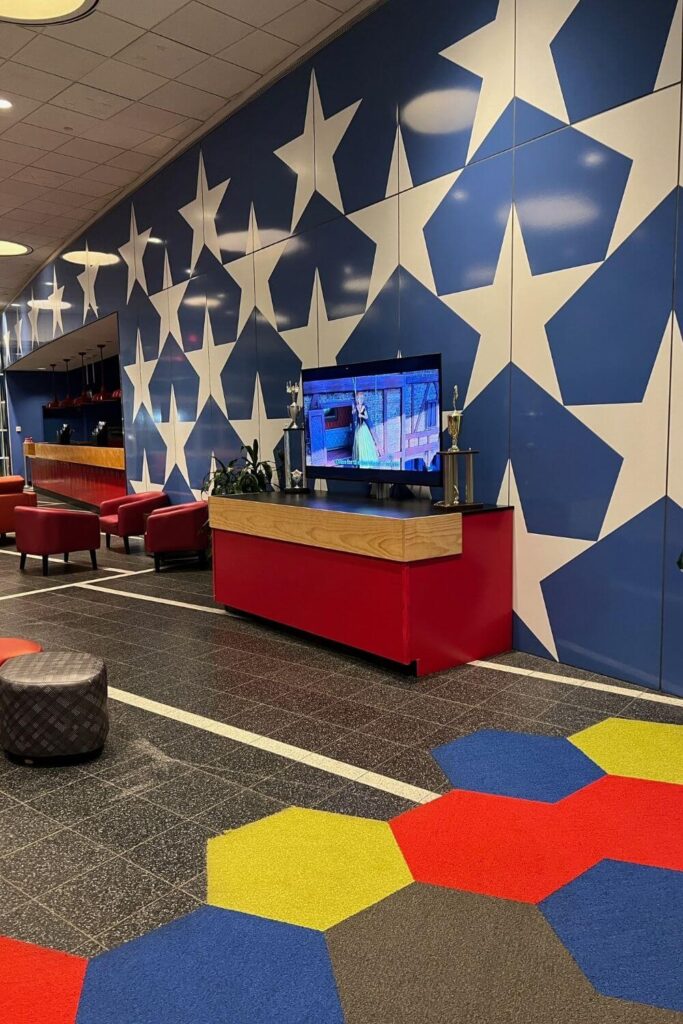 Photo of the All-Star Sports lobby with a television playing Frozen with small chairs and a rug for children to play.