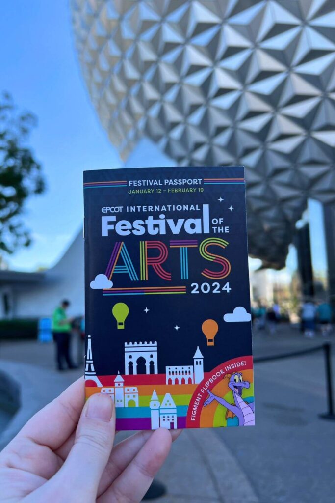 Photo of the 2024 Epcot International Festival of the Arts passport with Spaceship Earth in the background.