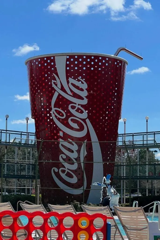 Photo of a 3-story tall coca-cola cup with a pool in the foreground.