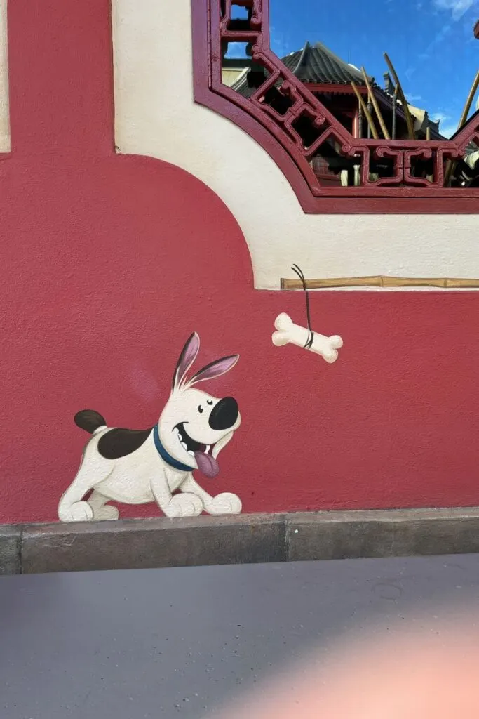 Photo of a chalk drawing of Little Brother, a pet dog from Mulan, on one of the building in the China pavilion in Epcot.