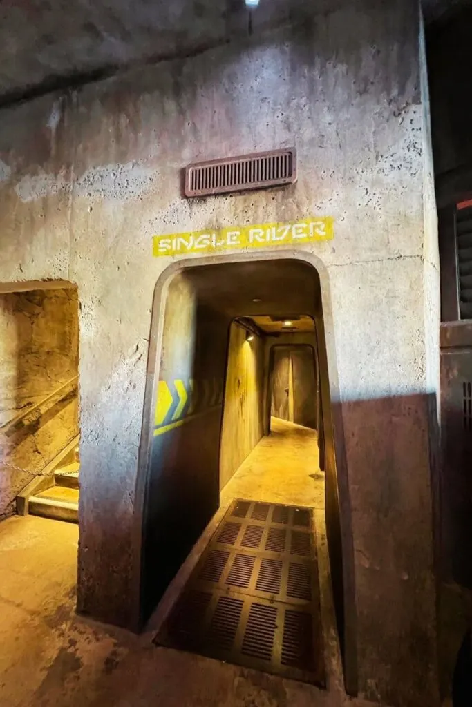 Photo of a long hallway with a sign above that reads: Single Rider at Millennium Falcon: Smugglers Run.