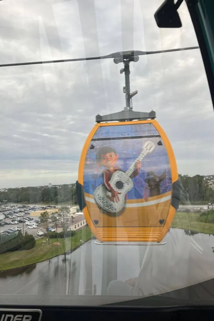 Photo of a Coco-themed Skyliner pod passing by from inside another pod.