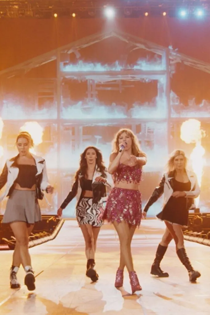 Photo of Taylor Swift and backup dancers performing a song from the 1989 album, while a house in the background burns down.