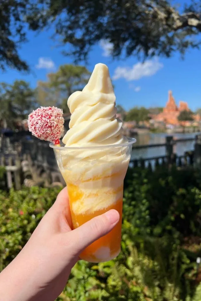 Closeup photo of a Dole Whip float with Magic Kingdom's Big Thunder Mountain in the background.