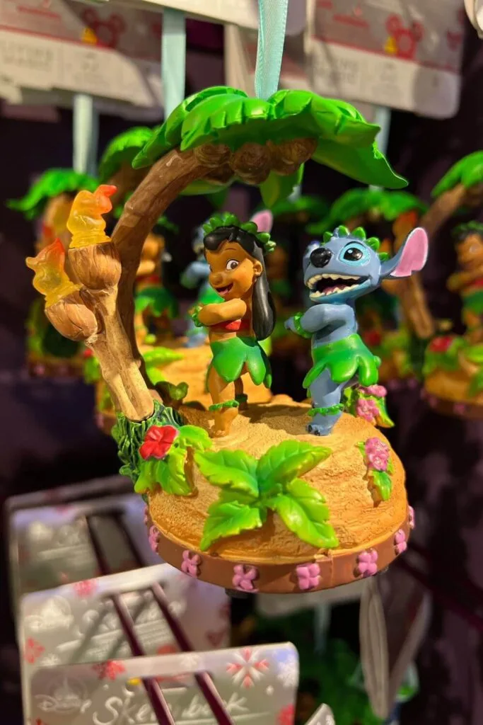 Photo of a Lilo & Stitch ornament with both characters doing a hula dance while wearing grass skirts and flower crowns.