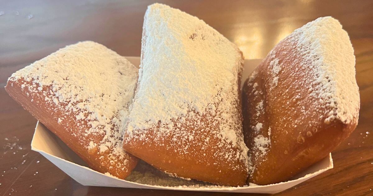 Closeup of a basket of fresh beignets covered in powdered sugar.