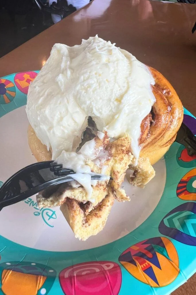 Photo of a giant cinnamon roll covered with a thick dollop of orange cream cheese icing.