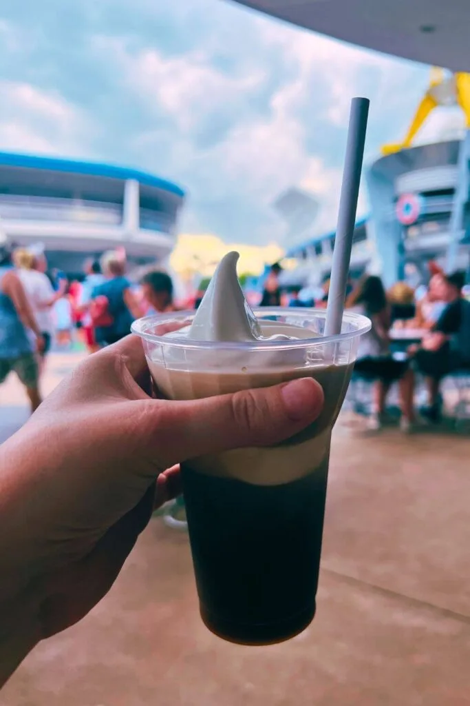 Closeup of Cold Brew Soft Serve Float from Auntie Gravity's with Magic Kingdom's Tomorrowland in the background.