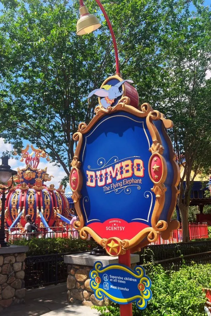 Photo of the sign for Dumbo The Flying Elephant ride with the ride in the background.
