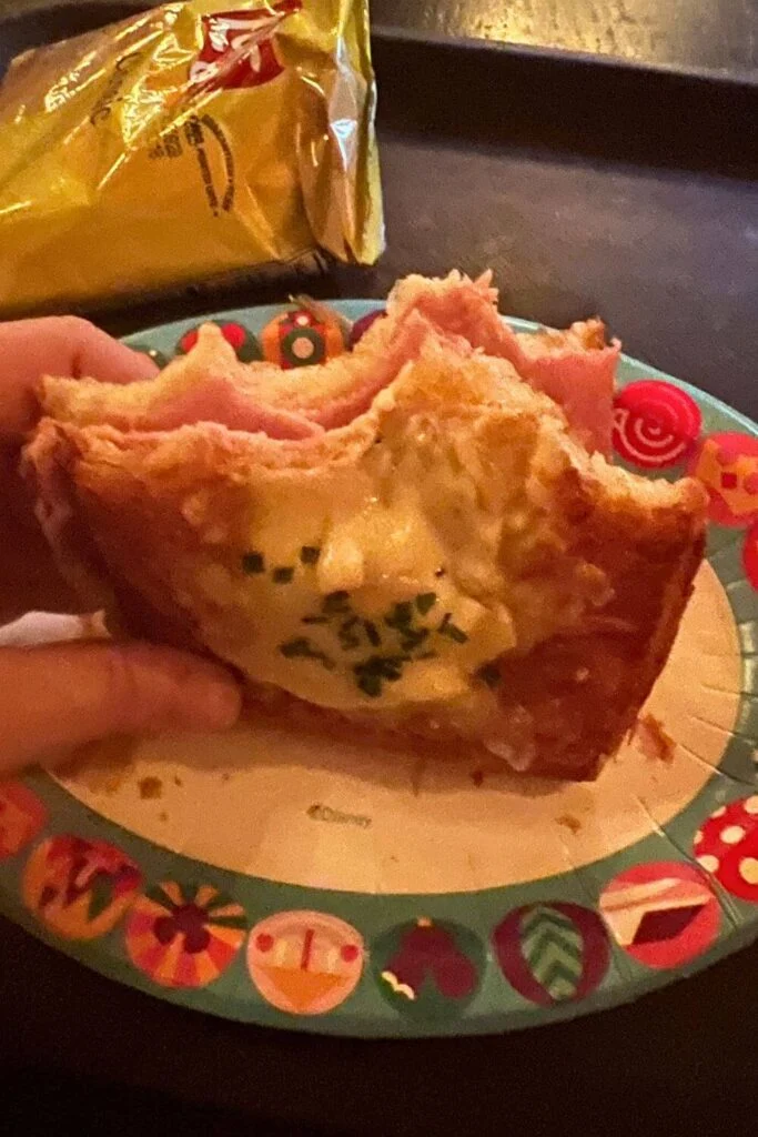 Closeup of the Ham & Gruyere Toastie from Gaston's Tavern, with bites taken out of the sandwich and a bag of potato chips in the background.