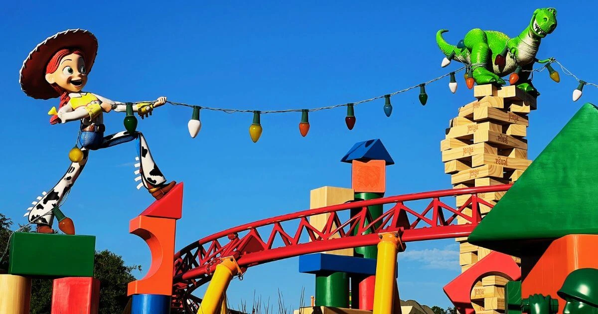 Photo of Jessie and Rex stringing up lights above Slinky Dog Dash roller coaster at Hollywood Studios' Toy Story Land.