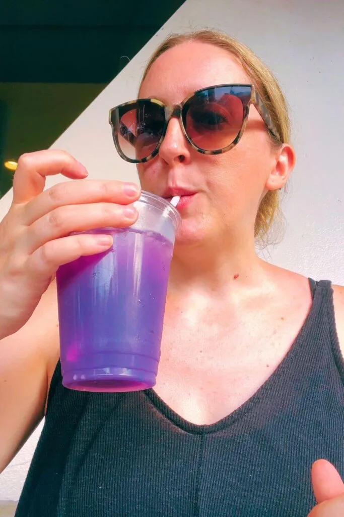 Photo of Meg Frost sipping a neon violet lunar lemonade from Cosmic Ray's at Magic Kingdom.