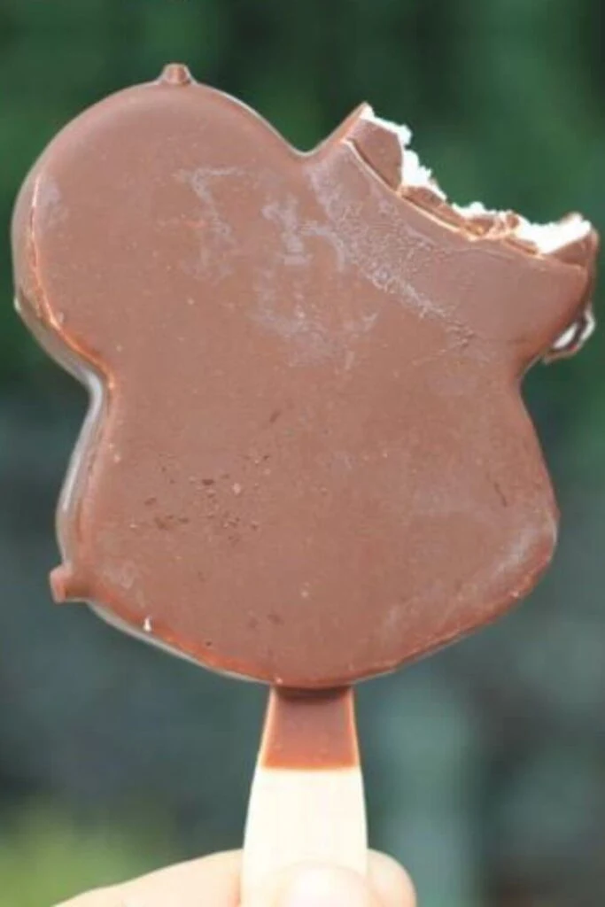 Closeup of a Mickey Mouse shaped ice cream bar with vanilla ice cream and chocolate shell.