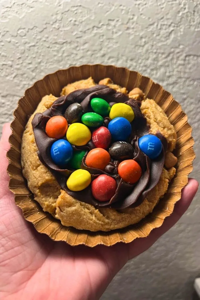 Photo of the peanut butter cookie pie topped with chocolate frosting and M&Ms.