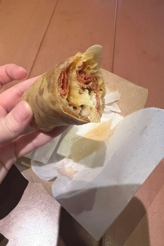Closeup of a half eaten pepperoni pizza spring roll from Magic Kingdom.
