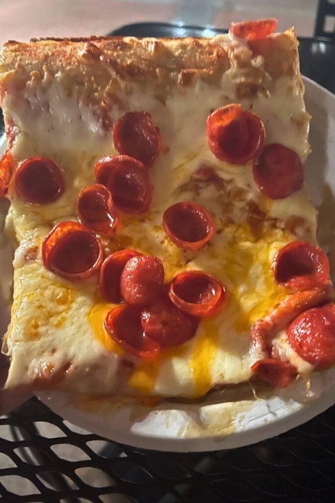 Closeup of a square of pepperoni pizza with cupped pepperoni.