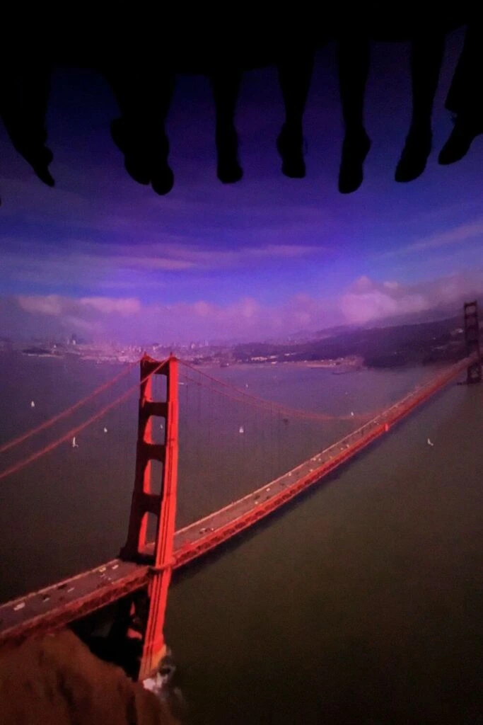 Photo of a scene from Soarin' California featuring the Golden Gate Bridge with feet dangling from the top.
