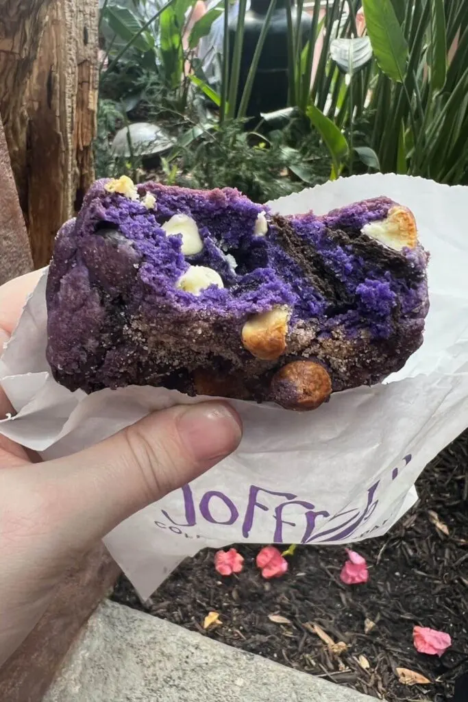 Photo of the purple Tower of Terror Cookie from Hollywood Studios, with a few bites taken out to show how thick it is.