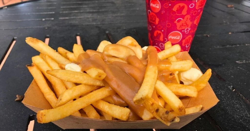 Closeup of a basket of poutine or french fries covered in cheese curds and brown gravy.
