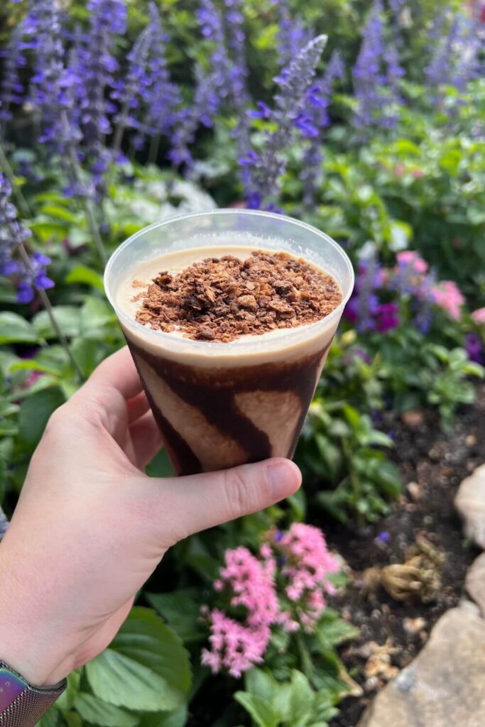 Photo of chocolate viking coffee with a garden filled with purple flowers in the background.