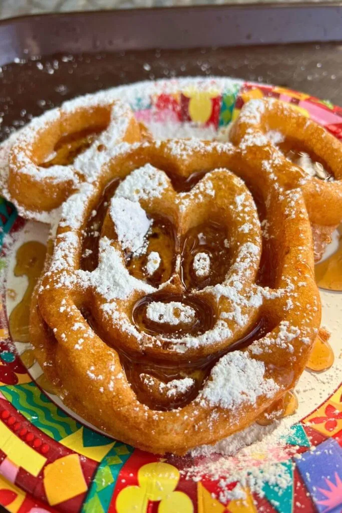 Photo of a giant Mickey shaped waffle covered in maple syrup and powdered sugar.
