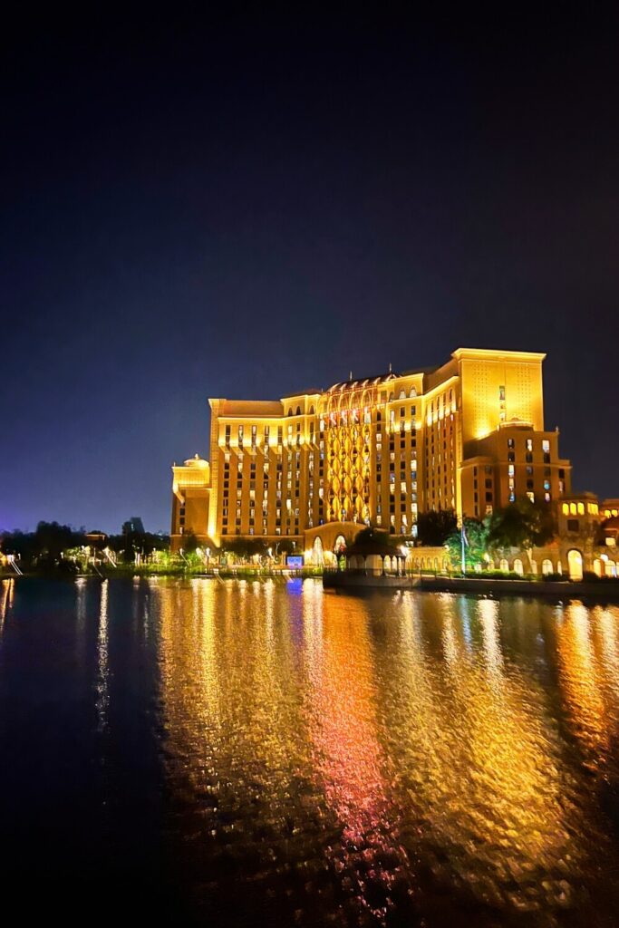 Photo of the Gran Destino tower at Disney's Coronado Springs Resort at night, with lights reflecting in the lake in front of it.