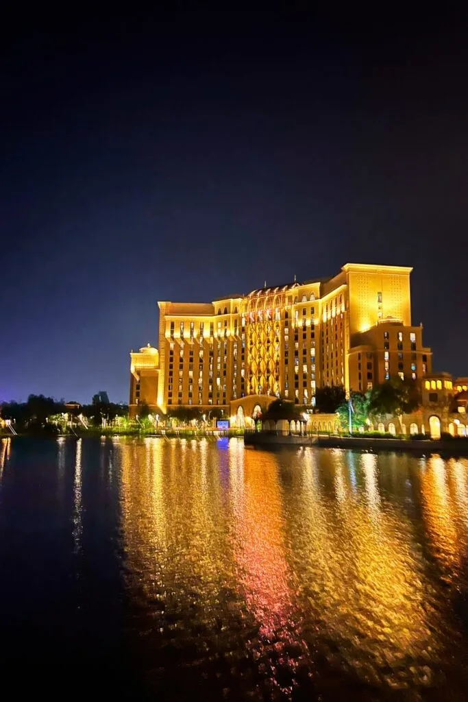 Photo of the Gran Destino tower at Disney's Coronado Springs Resort at night, with lights reflecting in the lake in front of it.